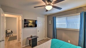 A bedroom with a bed, ceiling fan, TV, and a window with blinds. - Silver Modern 2BR: Pet-Friendly Oasis w/ Fenced Private Garden Near Downtown (Carmichael)