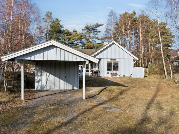 Een tweelaags huis met garage, overdekte veranda en een klein terras.