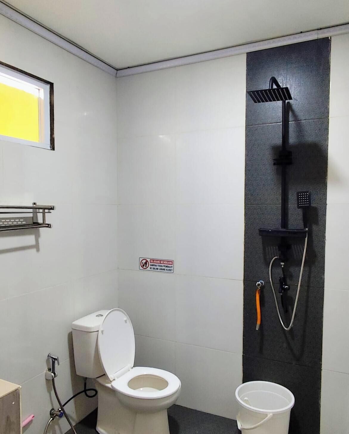 A small, clean bathroom with a toilet, a shower, and a hand dryer.