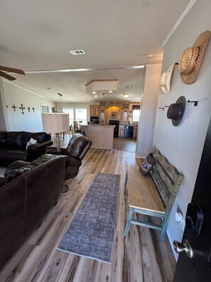 Un salon spacieux avec un canapé en cuir, un banc en bois et un tapis.