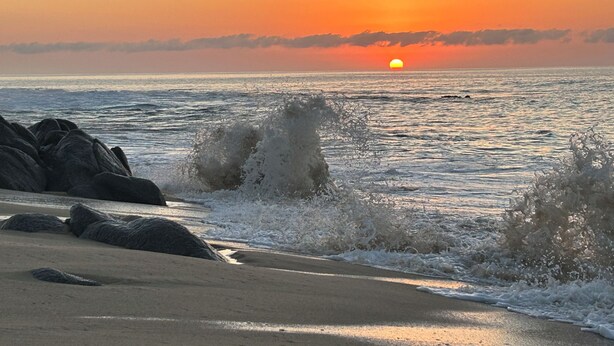Platja amb onyes, roques i un capvespre.