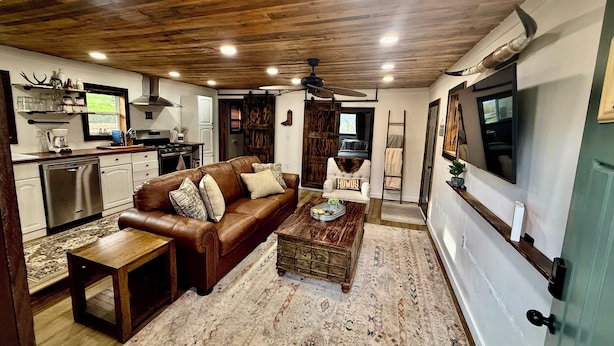 A living room with a brown leather sofa, a coffee table, and a television.