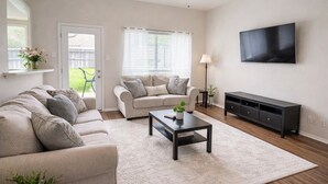 A living room with a sofa, a coffee table, a TV, and a TV stand.