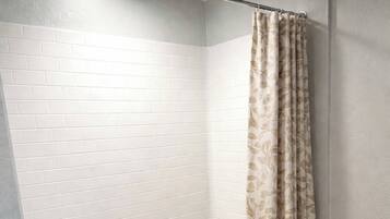 A bathroom with a white tiled wall, a bathtub, and a shower curtain.