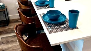 A modern kitchen with a white countertop, blue dishware, and wooden chairs. - Resort 1BR Oasis Pool Spa Gym Reno Getaway (Reno)