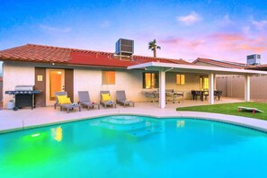 A residential building with a swimming pool, outdoor seating, and a covered patio area. - Luxury 4BR Retreat with Pool, Arcade, and Games (Henderson)