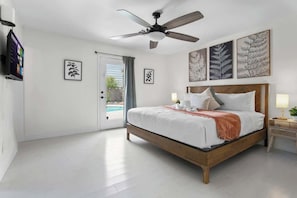 A bedroom with a bed, ceiling fan, artwork, and a view of the outdoors. - Luxury 4BR Retreat with Pool, Arcade, and Games (Henderson)