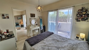 Een slaapkamer met een bed, een kaptafel met spiegel, een dressoir en een balkon met uitzicht.