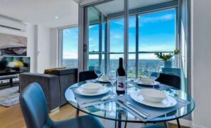 A dining area with a glass table, chairs, and a bottle of wine. - Magnificent Views - Bright & Spacious CBD Escape (Melbourne)