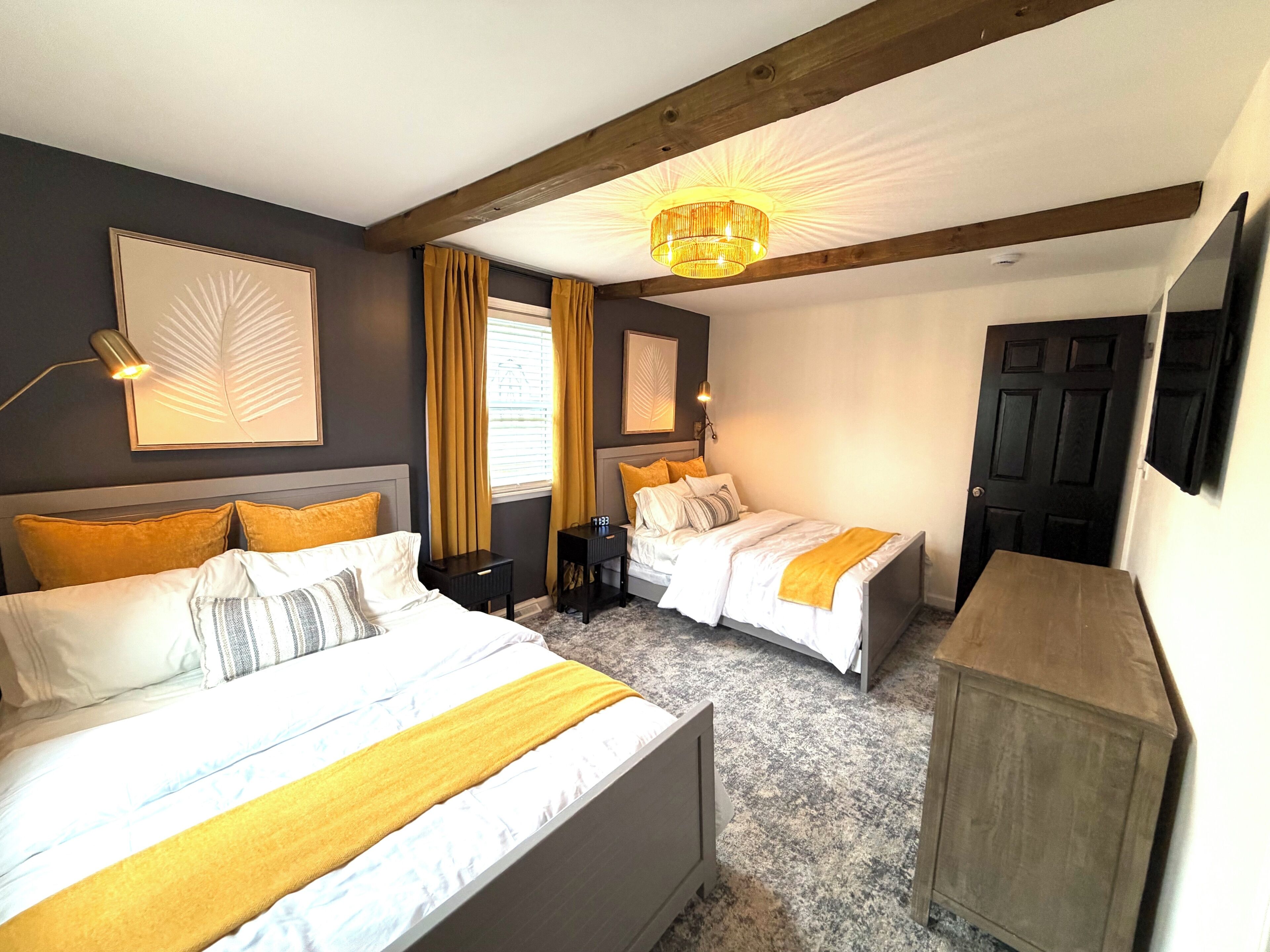 Une chambre d’hôtel avec deux lits, un plafond en bois, un lustre et un téléviseur.