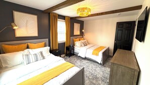 A hotel room with two beds, a wooden ceiling, a chandelier, and a television. - Barefoot Tiki Retreat -Inground Heated Pool, Hot Tub, Game Rm,Theater Rm,Firepit (Mason)
