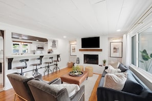 Een moderne woonkamer met een open haard, een bar en een groot raam.