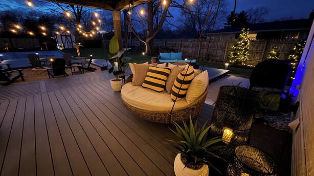 A covered outdoor seating area with a wicker sofa, potted plants, and string lights. - Barefoot Tiki Retreat -Inground Heated Pool, Hot Tub, Game Rm,Theater Rm,Firepit (Mason)