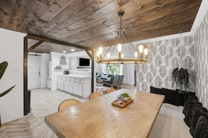 Een moderne keuken met witte kasten, een houten plafond en een hanglamp.