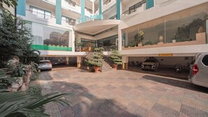 A multi-level hotel atrium with a central staircase, potted plants, and a car parking area. - Green Hotel Nha Trang (Nha Trang)
