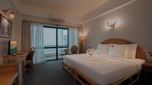 A hotel room with a large bed, a desk, a chair, a television, and a balcony with a view. - Green Hotel Nha Trang (Nha Trang)