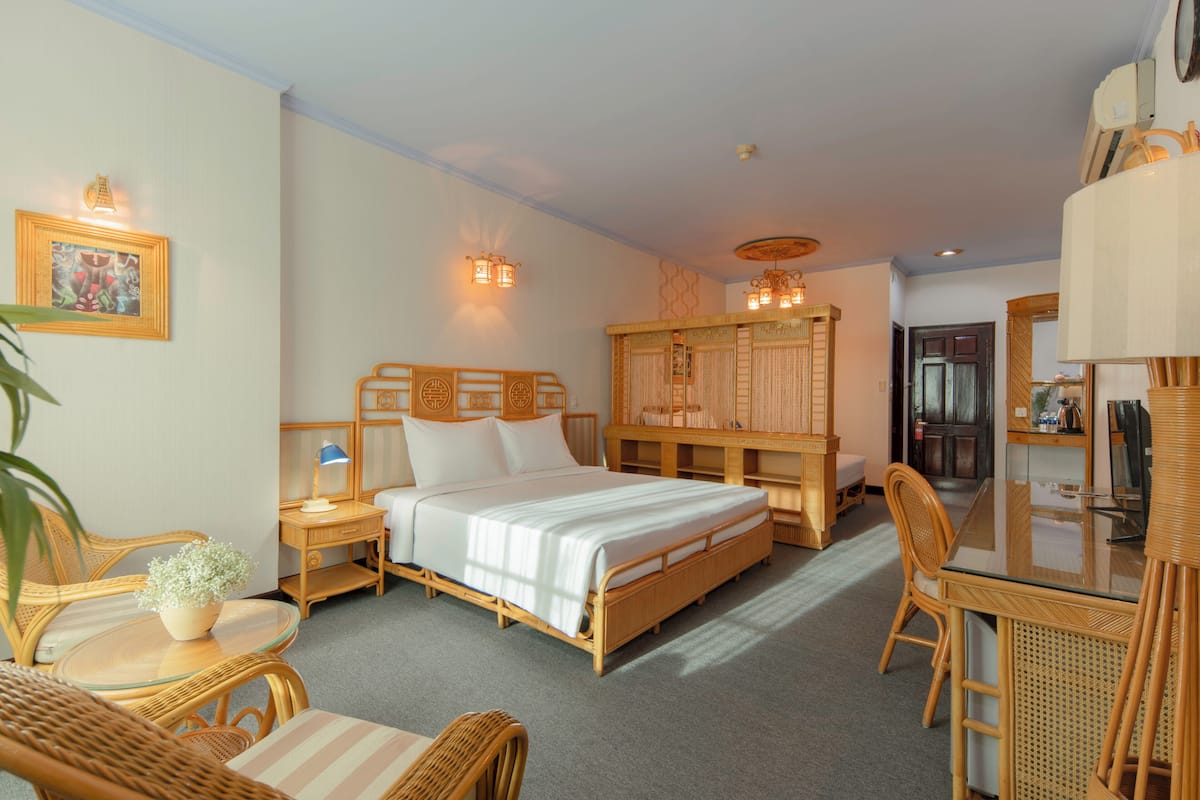 A hotel room with a bed, a desk, a chair, a small table, and a mirror.