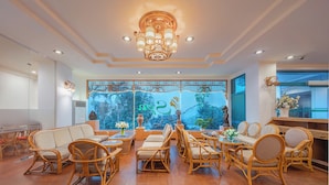 A spacious room with a large window, wicker furniture, and a decorative ceiling light. - Green Hotel Nha Trang (Nha Trang)