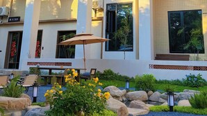 A multi-story hotel with balconies, large windows, and a landscaped garden with rocks and plants. - Quanzhou About Meisu (Quanzhou)