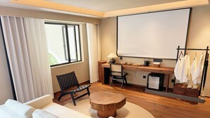A modern hotel room with a sofa, a wooden coffee table, a desk with a chair, a television, and a clothing rack. - Quanzhou About Meisu (Quanzhou)