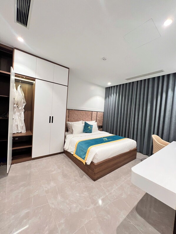 A modern hotel room with a bed, a wardrobe, a desk, and a chair.