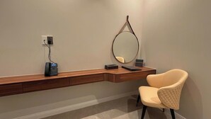 Une chambre moderne avec une console en bois, un téléphone, un miroir et un fauteuil rembourré.