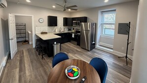A modern kitchen with a central island, stainless steel appliances, and a dining area with blue chairs. - Downtown Jim Thorpe Stay at Charles Albright (Jim Thorpe)