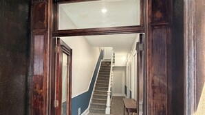 A hallway with a wooden door frame, a carpeted floor, and a staircase leading to another room. - Downtown Jim Thorpe Stay at Charles Albright (Jim Thorpe)