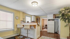 Une cuisine de taille réduite avec un tabouret de bar, un réfrigérateur et une plante en pot.