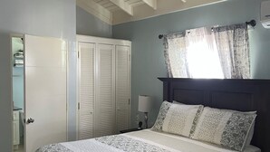 A bedroom with a bed, a ceiling fan, a nightstand, a lamp, and a window with curtains. - Cozy 2-bedroom house in peaceful Florence Hall Village with AC (Florence Hall Village)