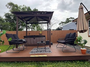 A deck with two chairs, a small table, a hot tub, and a pergola. - Spacious 3BR w/ Hot Tub, Grill & Game Room Near NRG, Med Ctr, Downtown & Hobby (Houston)