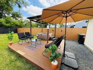 Eine überdachte Terrasse mit Gartenmöbeln, einem Whirlpool und einem Holzdeck.
