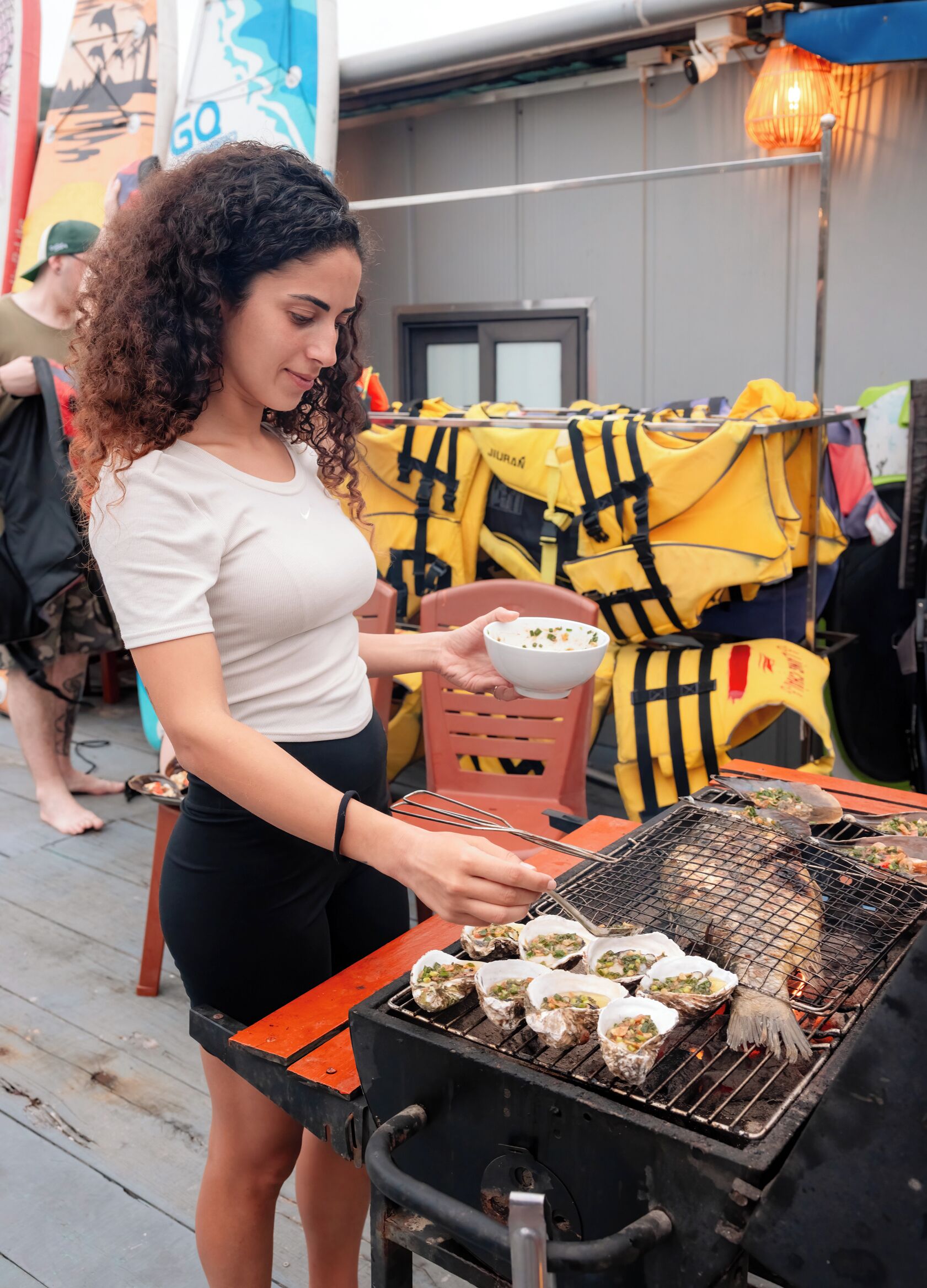 A person grilling oysters on an outdoor grill.
