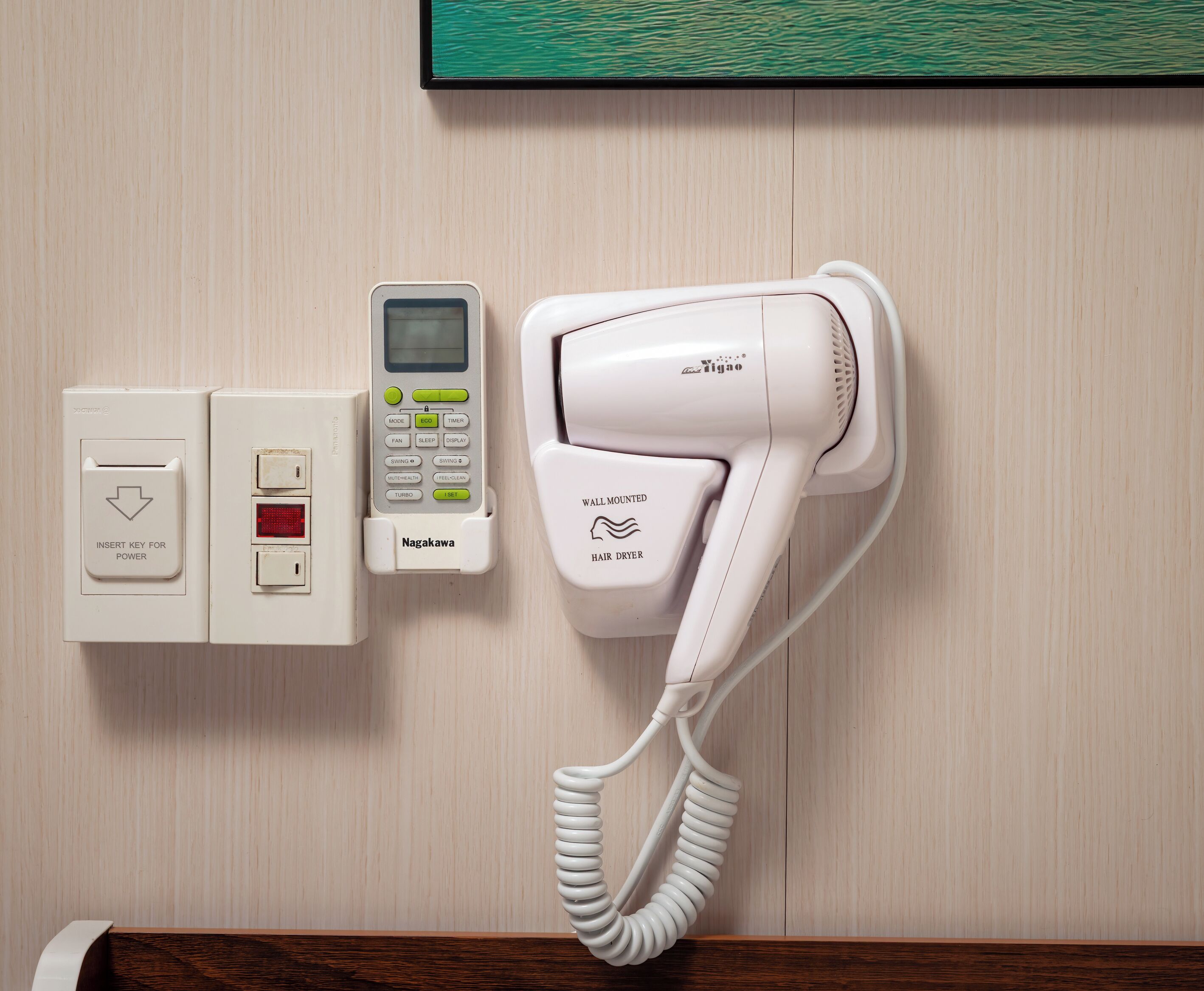 A wall-mounted hair dryer and a control panel with a digital display and buttons.