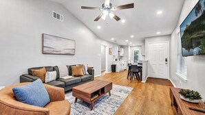 Un soggiorno moderno con divano, tavolino da caffè e ventilatore a soffitto.