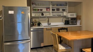 A compact kitchen with a refrigerator, microwave, sink, and wooden dining table. - Sweet One Bedroom (Victoria)
