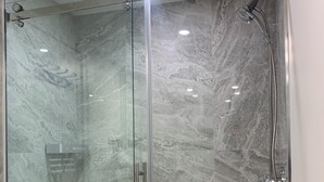 A glass-enclosed shower with a handheld showerhead, a handheld showerhead, and a handheld showerhead. - Sweet One Bedroom (Victoria)