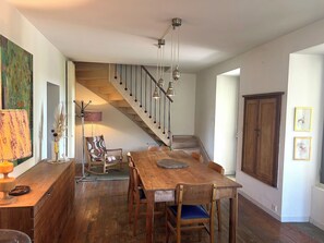 Ein Essbereich mit Holztisch und Stühlen, eine Treppe mit Geländer und ein Holzschrank.