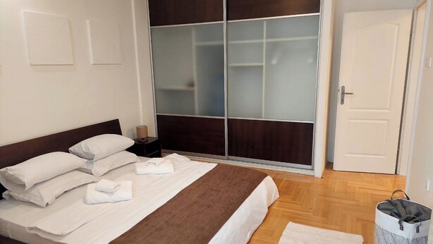Ein Hotelzimmer mit einem Bett, einem Kleiderschrank, einer Tür und einem Mülleimer.