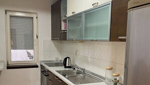 Eine Küche mit einem Edelstahl-Kühlschrank, einem Einbauofen, einer Spüle und Schränken.
