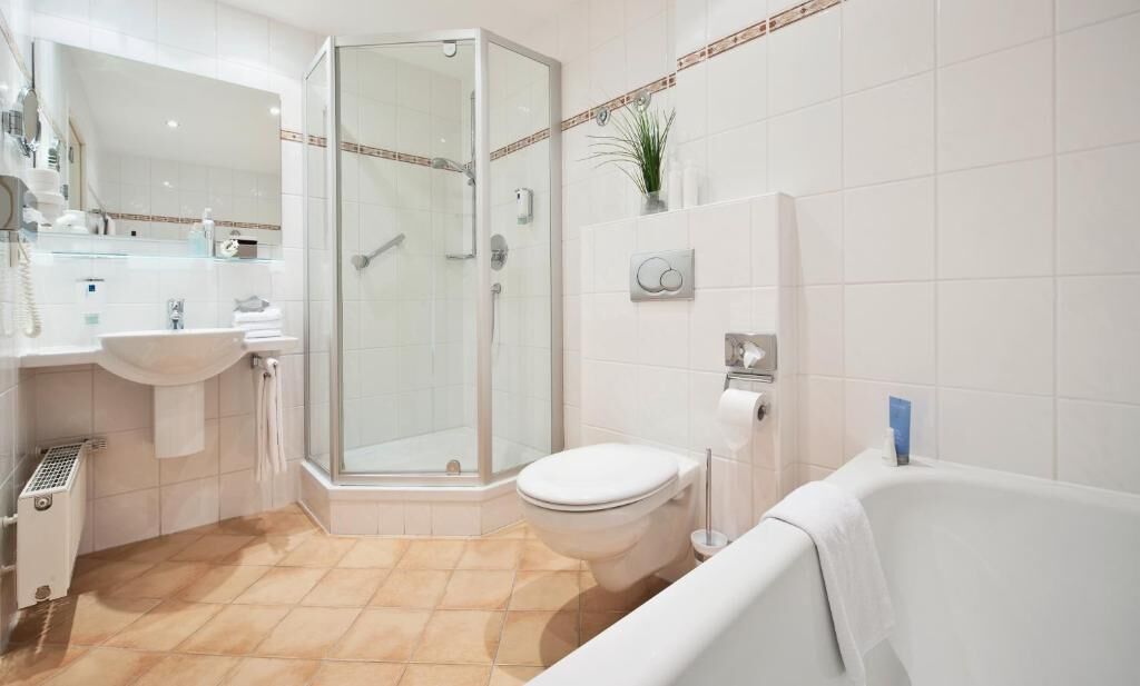 Un baño moderno con ducha envuelta en vidrio, un lavamanos blanco y una bañera.