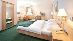 A hotel room with a bed, bedside table, lamp, and a desk with a chair. - Gasthof zum weißen Lamm (Sommerach)