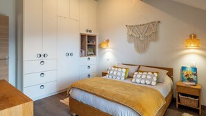 Quarto com cama, guarda-roupa, mesa de cabeceira e luzes na parede.