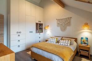 Une chambre à coucher comprenant un lit, une armoire, une table de chevet et des lampes fixées au mur.