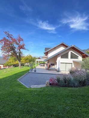 A modern house with a covered patio, a well-maintained lawn, and a clear blue sky.