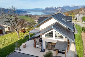 A modern house with a sloped roof, large windows, and a patio area with outdoor furniture.