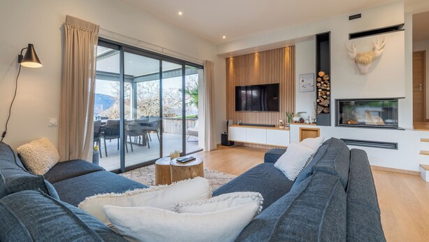 Uma sala de estar moderna com sofá, televisão, lareira e uma janela grande.