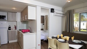 A compact kitchenette with a microwave, toaster, and sink. There is a dining area with a table, chairs, and a window with curtains. - Vigna Sul Mar Family Collection (Comacchio)