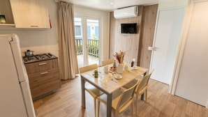 A modern kitchen with a gas stove, wooden cabinets, and a dining area with a table and chairs. - Vigna Sul Mar Family Collection (Comacchio)