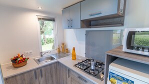 A compact kitchen with a gas stove, sink, and a microwave. - Vigna Sul Mar Family Collection (Comacchio)